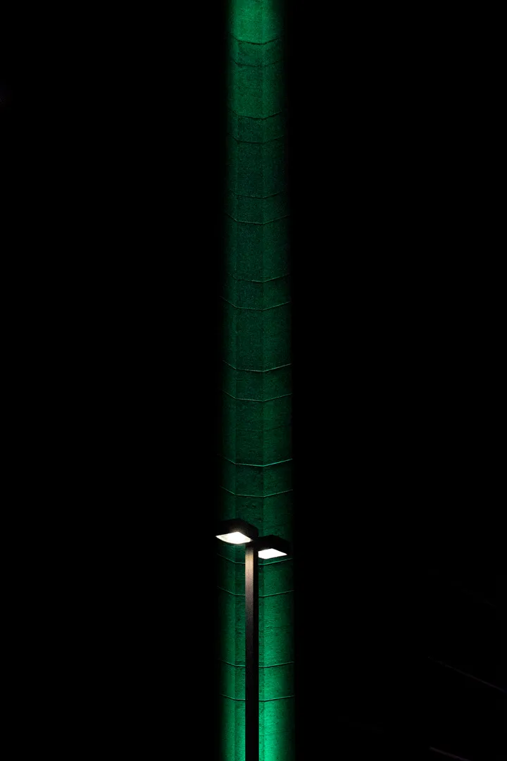A green beam of light reaching into the sky; downtown Boise dawn, with a parking lot light visible at the base