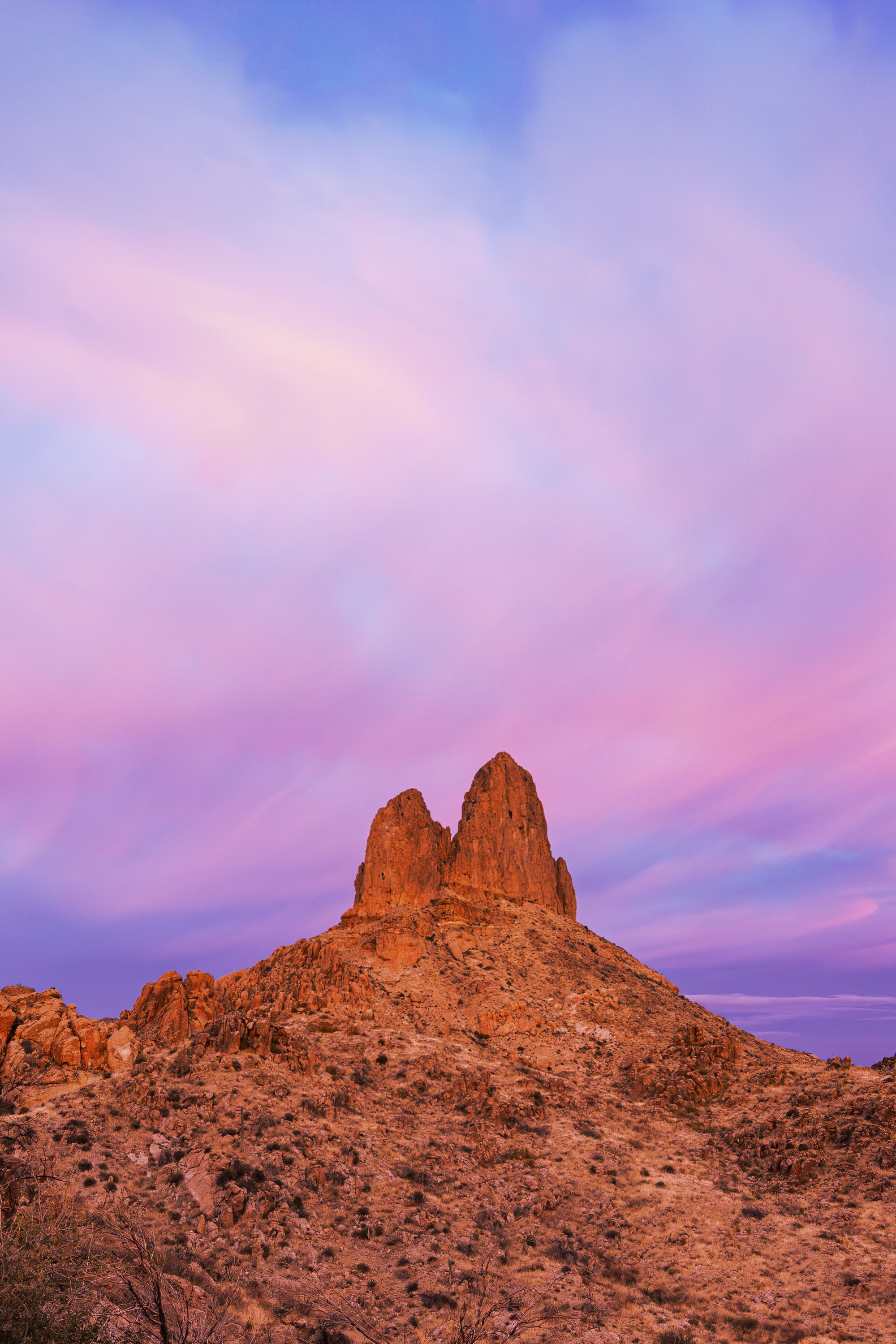 Weavers Needle rock formation in Arizona lit by warm sunrise light over desert terrain