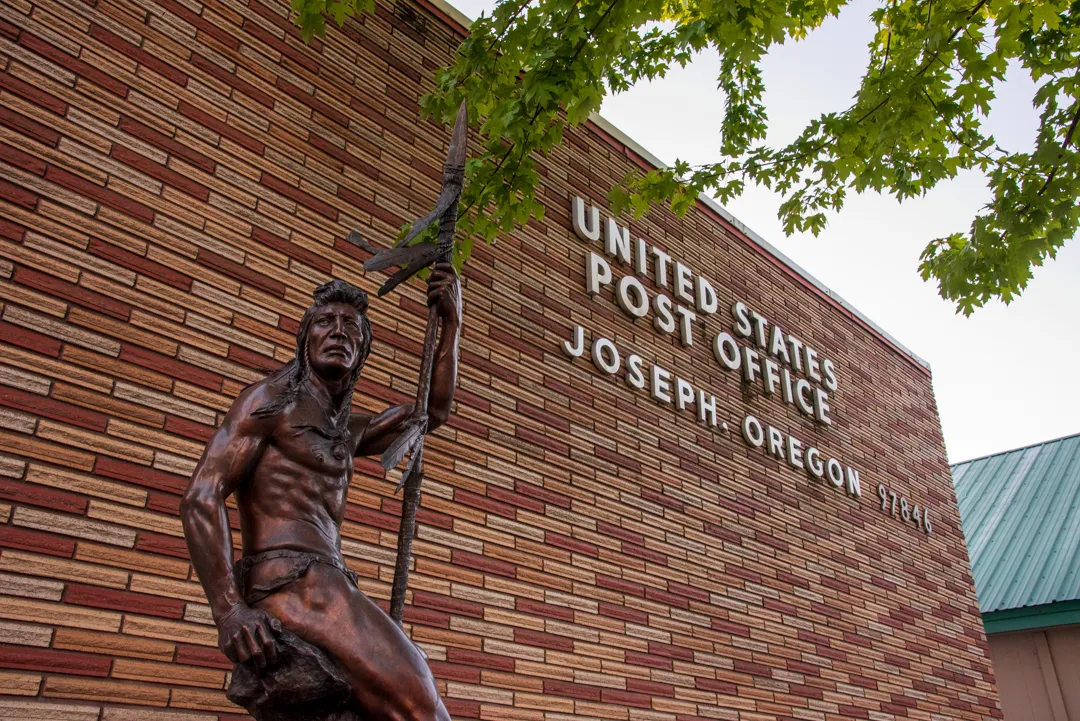 A bronze statue called The Sentinel by sculptor Austin Barton depicting a Nez Perce warrior holding a spear, standing beside the United States Post Office in Joseph, Oregon