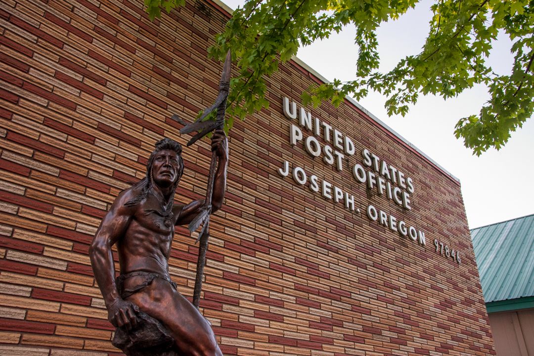 A bronze statue called The Sentinel by sculptor Austin Barton depicting a Nez Perce warrior holding a spear, standing beside the United States Post Office in Joseph, Oregon